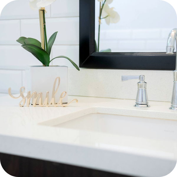 Close up image of a clean sink with flower pot and metal smile sign