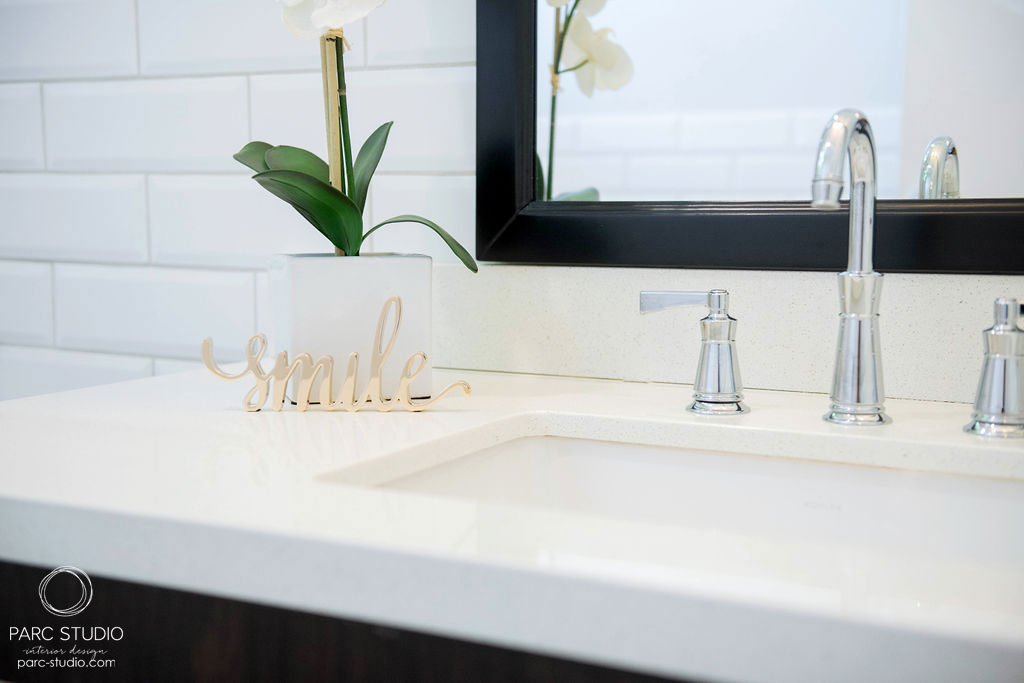Close up image of a clean sink with flower pot and metal smile sign